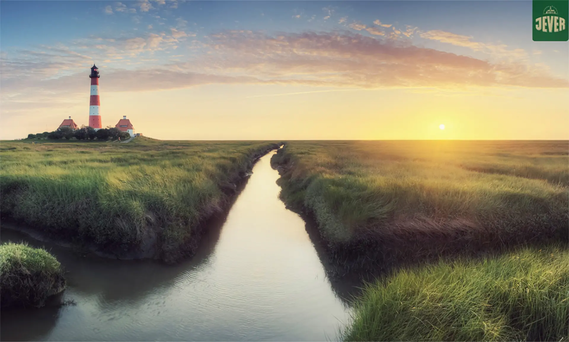 Op een met gras begroeide kust staat een vuurtoren, met een moerassige kreek die zich een weg baant naar een vredige zonsondergang.